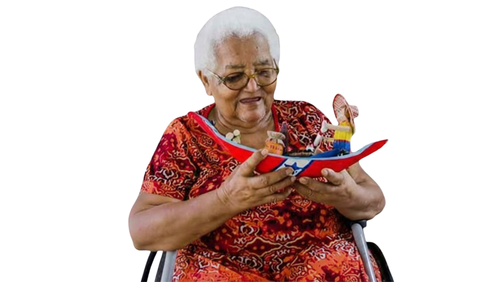 Mestra Nina abreu na cadeira de rodas segurando um brinquedo de miriti